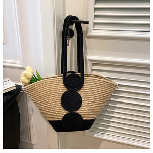 Detail of hand-woven bucket bag with black circular accents on a white wooden door