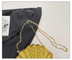 Gros plan détaillé du sac coquillage doré avec texture ondulée et fine bandoulière chaîne