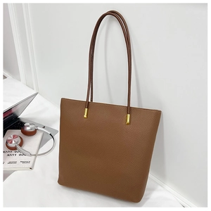 Détail de la texture du cuir litchi marron et boucle dorée sur le sac cabas pour femme