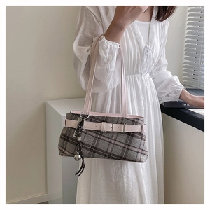 Detail of vintage plaid boston bag featuring pink leather straps and a silver bell charm