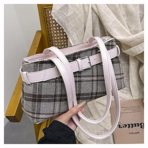Close-up of grey plaid boston bag with pink leather strap and soft tweed texture