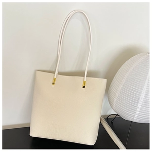 Gros plan du sac cabas en cuir beige grainé avec boucles métalliques dorées élégantes