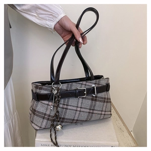Detail of vintage plaid pillow bag with brown leather straps and metallic bell charm