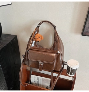 Brown semi-circular crossbody bag with white contrast stitching and puppy plush charm