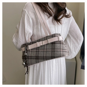 Close-up of vintage plaid Boston bag with pink leather trim and metal bell pendant