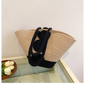 Macro shot of hand-woven beige straw tote with black circular weave details and rope handles
