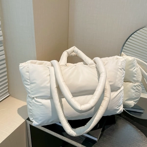 White puffy quilted tote bag with large capacity and thick handles in a warm interior setting