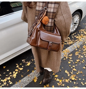 Brown vintage faux leather tote bag with pocket and teddy bear charm in autumn setting