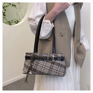 Detail of vintage grey plaid pillow bag with brown leather straps and metal buckle accent