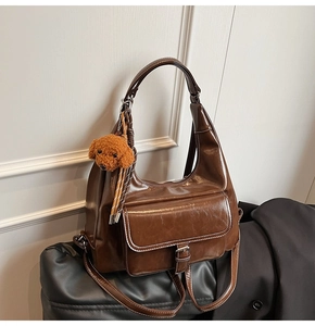 Detail of dark brown retro PU leather underarm bag with a cute plush teddy dog charm
