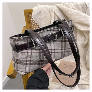 Detail of vintage grey plaid pillow bag with dark brown leather straps and metal buckles