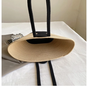 Detail of woven straw tote bag with black handles and spacious fabric interior