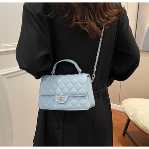 Close-up of light blue quilted crossbody bag with silver twist lock and chain strap