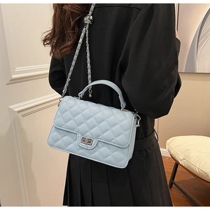 Detail of light blue quilted leather bag featuring silver metal twist lock and chain strap