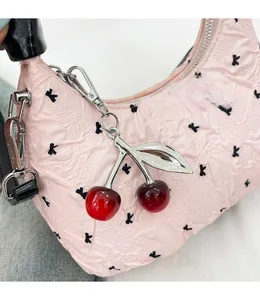 Detailed shot of pink textured handbag featuring cherry charm and black bow pattern