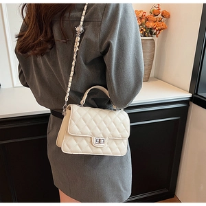 Close-up of quilted ivory crossbody bag with leather chain strap and silver twist lock