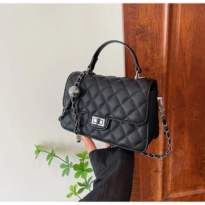 Detail of black quilted leather handbag featuring silver metal twist lock and chain strap