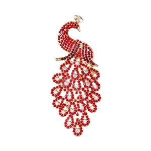 Détail d'une élégante broche paon avec strass rouges sur base en métal doré