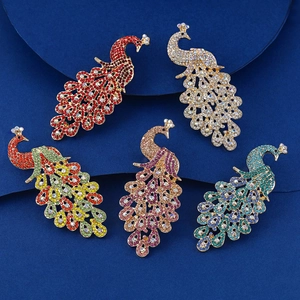 Vue détaillée de broches paon serties de cristaux en cinq couleurs sur socle bleu