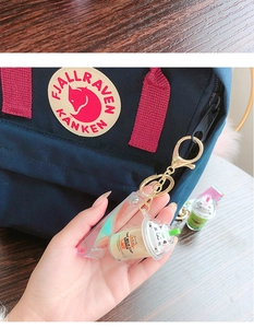 Detail of creative cat milk tea keychain with holographic strap on a backpack