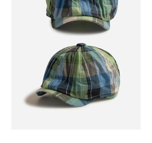 Detail of multi-color plaid newsboy cap showing woven fabric texture and top button