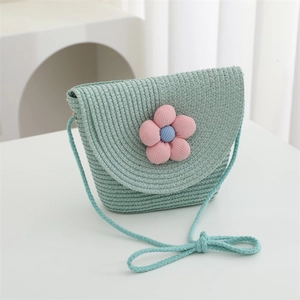 Detail of mint green woven straw bag featuring a decorative pink fabric flower