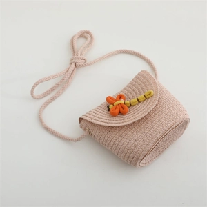 Detail of pink straw woven crossbody bag for girls with fabric dragonfly ornament