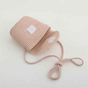 Detail view of pink straw woven crossbody bag with velcro closure and rope strap