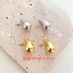 Close-up of small 2.5cm teardrop earrings in polished gold and silver metallic finish