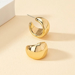 Macro shot of chunky gold-plated teardrop earrings with a polished mirror finish