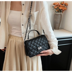 Side view of a quilted black leather crossbody bag on model with silver chain strap