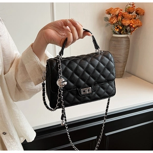 Detail of black quilted leather handbag featuring silver skull charm and chain strap