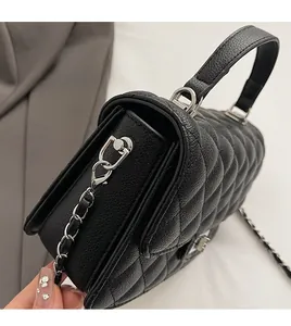 Detail of black quilted leather texture and silver chain strap on women's handbag