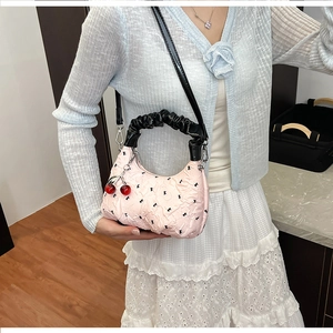 Pink pleated dumpling bag with black bow patterns and cherry charm shown on model