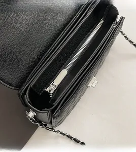 Close-up of a black quilted handbag showing silver zipper and rotating metal lock details