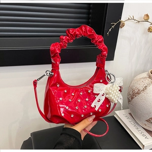 Detail of red patent leather cloud bag with rhinestone studs and pearl heart charm