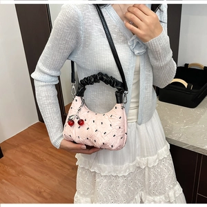 Detail view of pink ruched shoulder bag featuring black print and cherry charm accessory