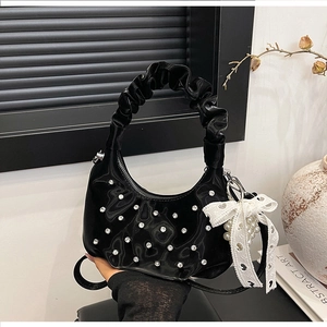 Detail of black pleated cloud bag with silver rhinestones and white lace bow accessory