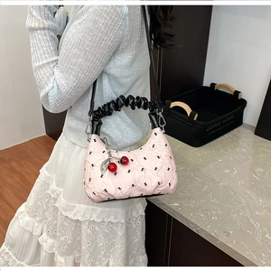 Detail of pink quilted handbag with black k print, cloud handle and cherry charm