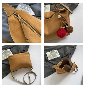 Detailansicht braune Wildledertasche mit goldenem Reißverschluss und Plüschanhänger