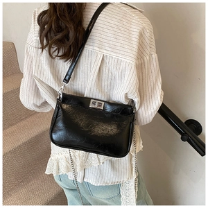Vista posteriore di una modella con borsa a tracolla in pelle nera lucida e fibbia argento