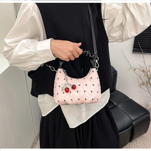 Detailed close-up of pink ruched dumpling bag featuring black K pattern and cherry charm