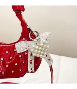 Detail of red patent leather pleated bag with rhinestone accents and heart pearl charm