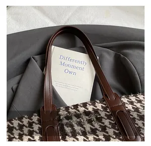 Detail of the brown leather handles and houndstooth fabric texture of the tote bag