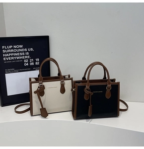 Detail of fashion tote bag showing leather texture and stitching with dual top handles
