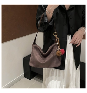 Detail of suede crossbody bag showing the soft texture and plush charm accessory