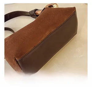 Close-up of brown suede and leather stitching with gold hardware on the bag base