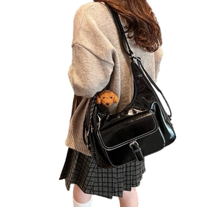Retro black glossy leather shoulder bag with white stitching and teddy bear charm