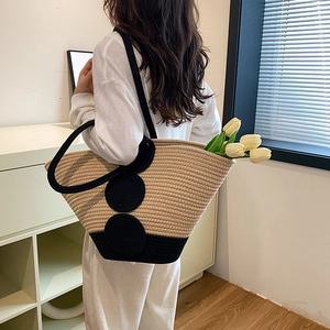 Handwoven beige and black contrast tote bag with circular accents and black handles