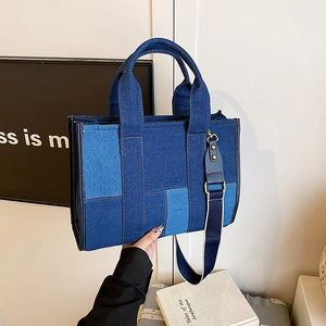Detail of multi-tone denim patchwork tote bag featuring contrast stitching and wide strap